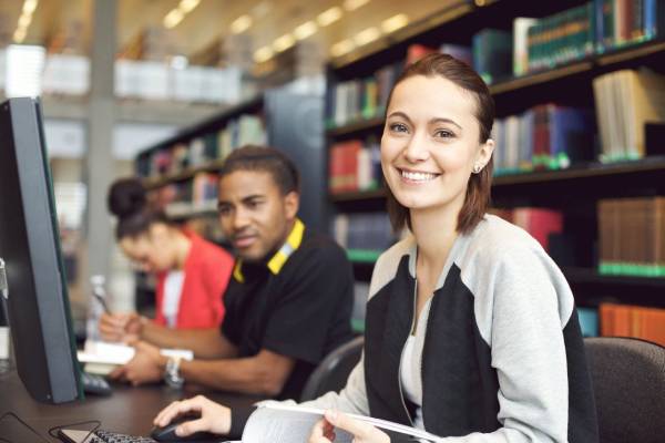 A group of people sitting at tables in a library.