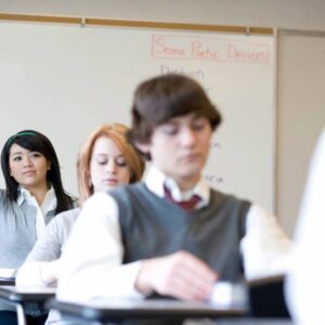 A group of students sitting at desks in front of a whiteboard.