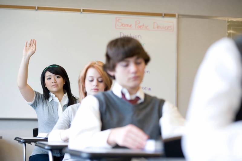 A group of students sitting at desks in front of a whiteboard.