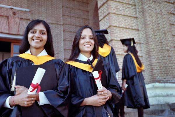 A group of women in graduation robes holding diplomas.