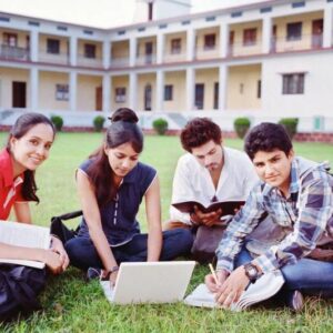 A group of people sitting on the grass with books and laptop