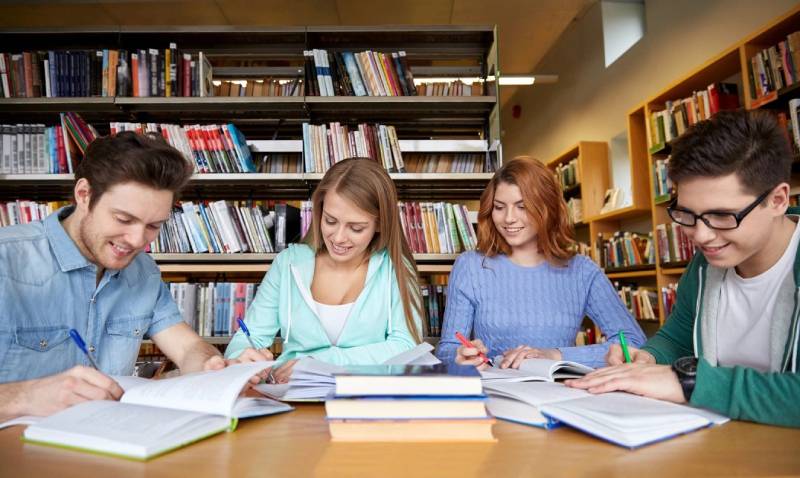 A group of people sitting at a table with books.