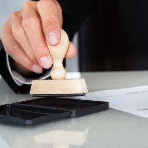 A person is using a rubber stamp on a table.